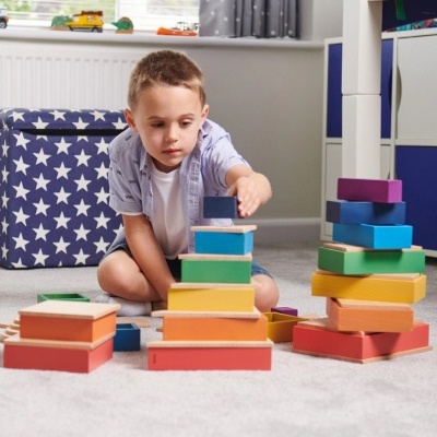 Criança a brincar com blocos de construção coloridos de madeira num quarto infantil