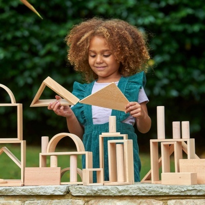 Criança a brincar com blocos de madeira ao ar livre