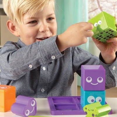 Criança a brincar com blocos coloridos sorridentes sobre uma mesa branca