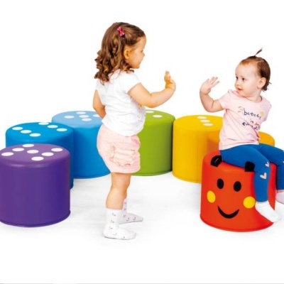 Duas crianças com puffs coloridos em forma de dados e blocos em fundo branco.