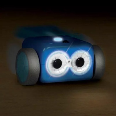 Robô pequeno azul com luzes frontais que parecem olhos em chão de madeira