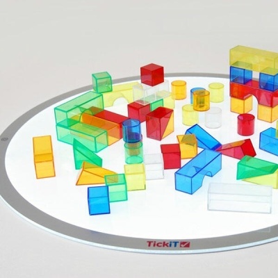 Blocos de construção coloridos transparentes num tabuleiro redondo branco com borda cinzenta e texto TickiT