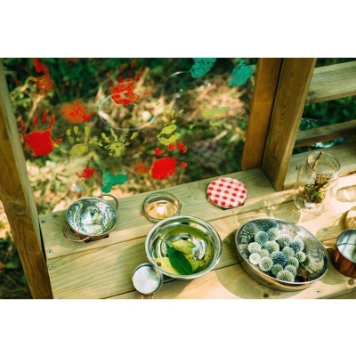 tigelas metálicas redondas sobre banco de madeira com tampa às riscas e mãos coloridas desenhadas no vidro