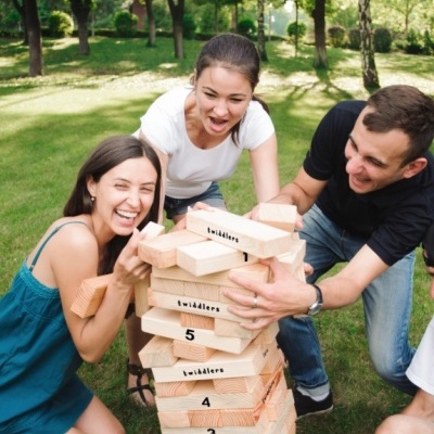 Três jovens a jogar jogo de peças de madeira grandes ao ar livre num jardim