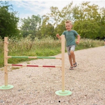 Kit de salto infantil em madeira com barras coloridas, exterior em terra batida com natureza ao fundo e crianças a correr
