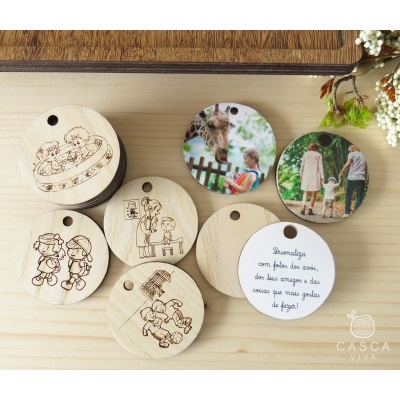 Etiquetas redondas de madeira e papel com ilustrações infantis, imagens a cores e texto em português, sobre fundo de madeira clara com flores