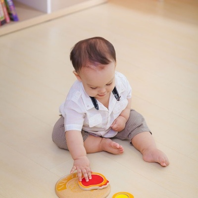 Criança a brincar com brinquedo de madeira colorido no chão