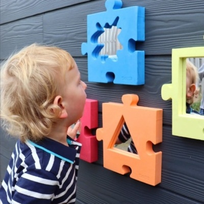 Peças de puzzle coloridas montadas na parede com uma criança a observar