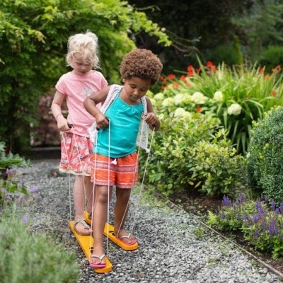 Duas crianças a brincar com escada de corda colorida num jardim