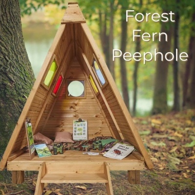 Cabana triangular de madeira com janelas coloridas numa floresta com livros e brinquedos