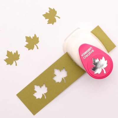 Perfuradora de papel rosa e branca com recortes de folhas de papel verde