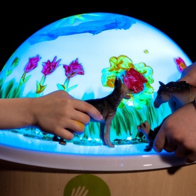 Mesa de luz redonda com desenhos coloridos e crianças a brincar com bonecos de animais