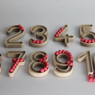Números de madeira com bolas vermelhas em superfície cinza