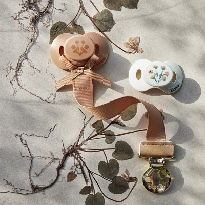 Dois chupetas com desenhos florais e clipe de fixação bege