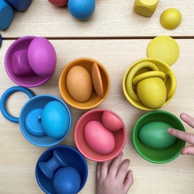 brinquedos de madeira coloridos em superfície de madeira clara com mãos de crianças