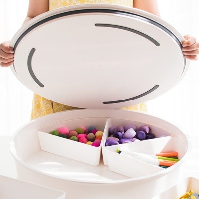 Caixa organizadora redonda branca com compartimentos e objetos coloridos