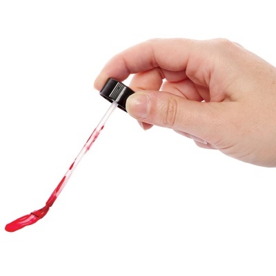 Mão segurando conta-gotas com líquido vermelho