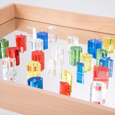 Peças coloridas de jogo de tabuleiro em acrílico numa caixa de madeira