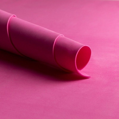 Tapete de yoga rosa parcialmente enrolado sobre uma superfície plana