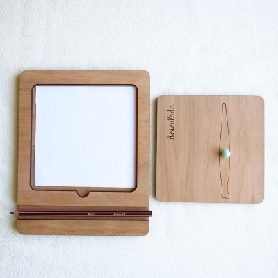 Suporte de madeira para lápis e caderno com suporte quadrado de madeira com texto 'āscuIpādo' e uma esfera azul-pálida suspensa por um fio.