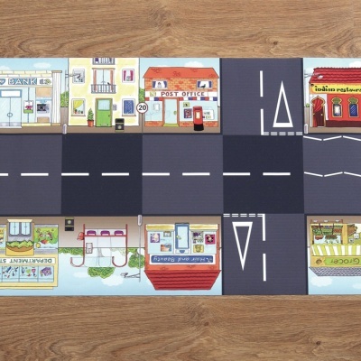 Tapete de jogo infantil com padrão de estrada e edifícios urbanos coloridos