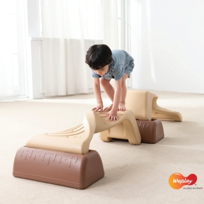 Criança a brincar em brinquedo modular de equilíbrio de plástico bege e castanho em ambiente interior