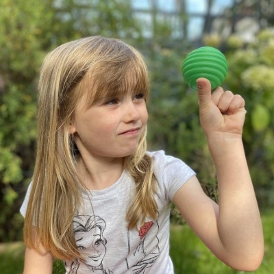 Menina com bola verde texturizada ao ar livre