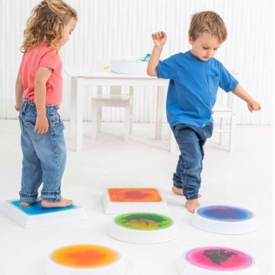 Crianças usando bases sensoriais coloridas num espaço branco