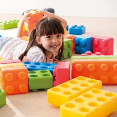 Criança sorridente com blocos de construção coloridos grandes