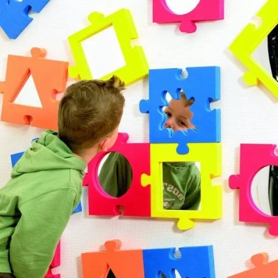Peças de puzzle coloridas com espelhos embutidos numa parede branca