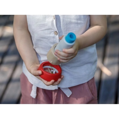 Criança segurando brinquedo de madeira colorido com peças vermelha e cinza com azul