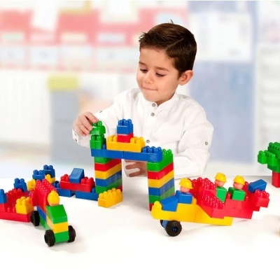 Menino a brincar com blocos de construção coloridos em mesa branca