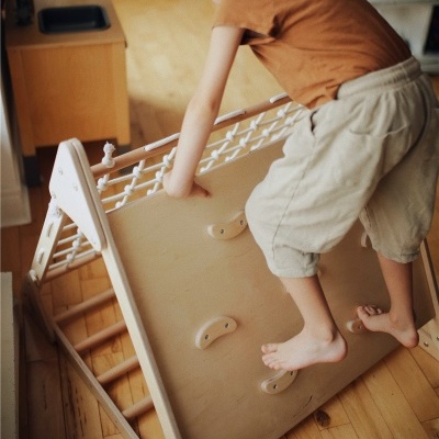 Criança a usar escada de madeira clara com cordas trançadas
