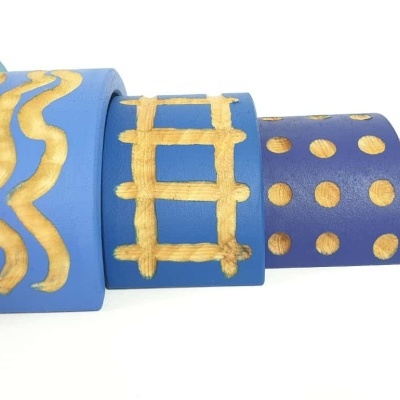 Cinco vasos cilíndricos coloridos empilhados com padrões dourados