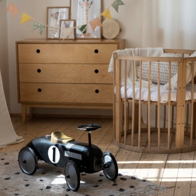 Quarto de bebé com berço redondo, cómoda, tapete e brinquedo carro preto