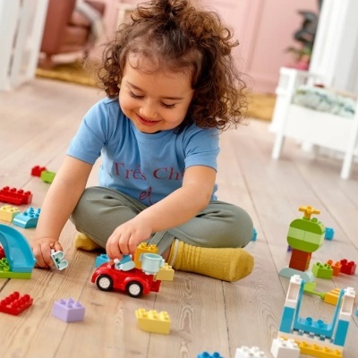 Criança a brincar com blocos de construção coloridos no chão de madeira