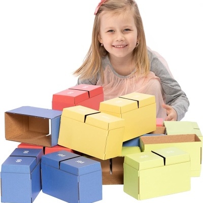 criança sorridente com caixas de papelão coloridas empilhadas