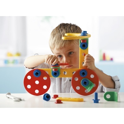 Menino a construir brinquedo colorido de plástico com parafusos e rodas vermelhas