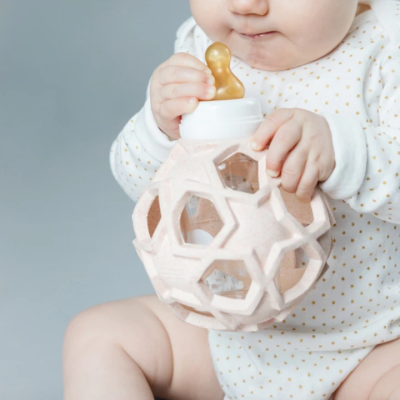 Bebé com bola de brinquedo rosa com tetina de biberão amarela