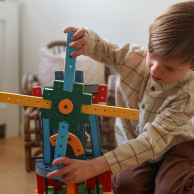 Criança a brincar com construção de madeira colorida sobre tapete