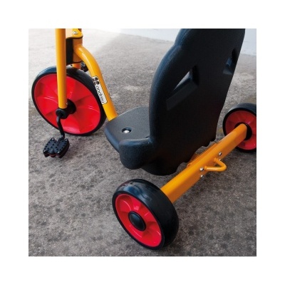 Triciclo infantil amarelo e vermelho com assento preto em piso cinzento