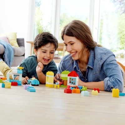 Criança e mulher a jogar com blocos de construção coloridos no chão