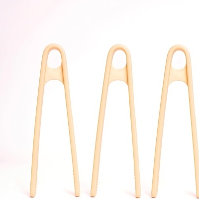 Três pinças de cozinha beje em pé sobre fundo branco