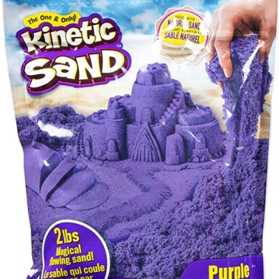 Pacote de areia cinética roxa com castelo de areia moldado e mão a pegar areia