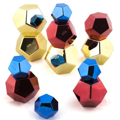 Peças poliedricas metálicas em azul, vermelho e dourado brilhante empilhadas sobre fundo branco
