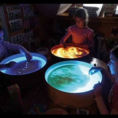 Crianças a brincar com bandejas luminosas com areia colorida