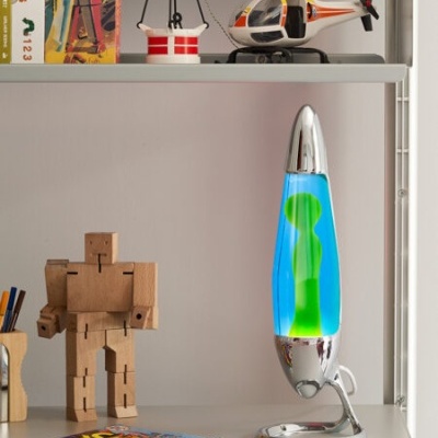 Lâmpada lava azul e verde com base cromada numa prateleira com brinquedos e livros
