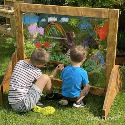 Dois meninos pintam em quadro transparente com moldura de madeira.