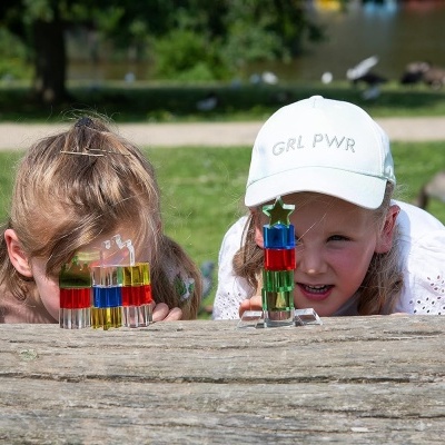 Duas crianças a brincar com peças de encaixe coloridas em parque ao ar livre.