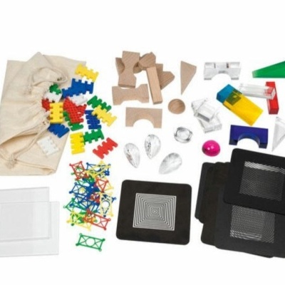 Peças de construção multicoloridas e prismas transparentes organizados em superfície branca.